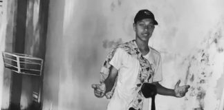 Adolescente de 16 anos morre após conflito familiar em Itapevi Fotografia em preto e branco de um adolescente posando em frente a uma parede, com uma motocicleta visível parcialmente. Imagem vinculada a redes sociais, usada para identificação do jovem falecido e tratada como foto de arquivo.
