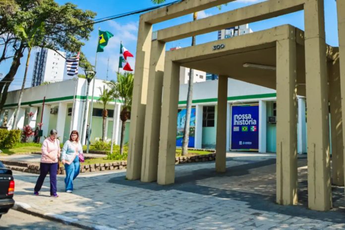 Prédio da Prefeitura de Osasco, com bandeiras e pessoas em frente, ilustrando a administração municipal.