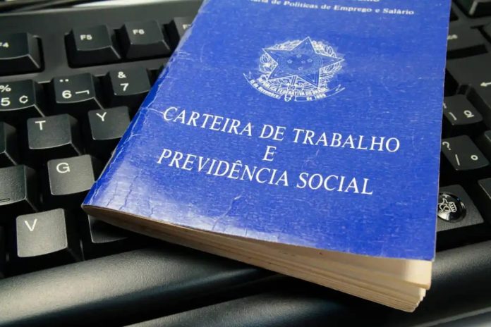 Carteira de Trabalho e Previdência Social sobre teclado de computador, ilustrando documentos necessários para processos seletivos no PAT de Santana de Parnaíba.