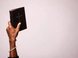 Justiça mantém demissão por justa causa de trabalhador que apresentou 88 atestados e atuou como pastor Pessoa segurando uma Bíblia durante culto religioso