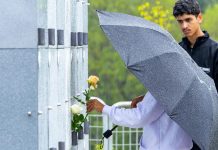 Itapevi promove atividades e transporte gratuito em cemitérios no Dia de Finados Visitantes realizam homenagem no cemitério municipal sob chuva, protegidos por guarda-chuva