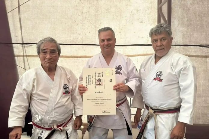 Gilberto de Mello Schavareto Junior, técnico de karatê de Osasco, segurando o certificado do título Renshi Shihan concedido pela IKGA, ao lado de dois mestres durante a cerimônia em Cartagena, Colômbia.