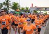 Circuito Nacional LIVE! RUN XP 2026 Chega a Barueri com Corridas e Atividades no Shopping Tamboré Participantes da LIVE! RUN XP usando camisetas laranja durante corrida, com faixa de largada ao fundo exibindo logo do evento