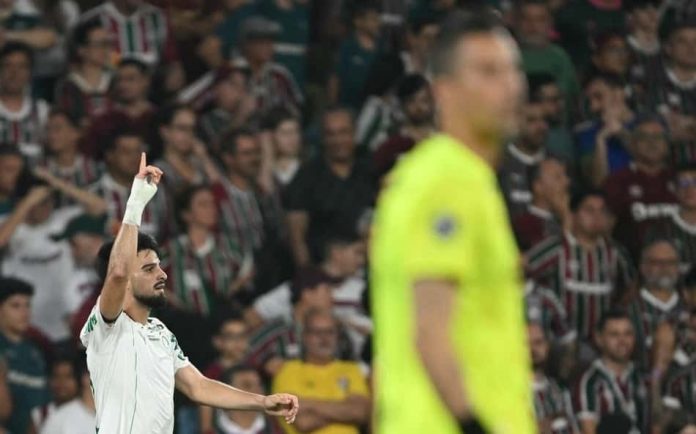 expresso-f8cd982500ecfbe50edfe6dc Jogador do Palmeiras comemora gol durante partida contra o Fluminense no estádio do Maracanã, com torcedores do Fluminense ao fundo e goleiro Fábio em primeiro plano.