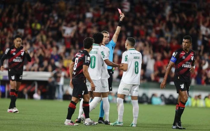 Árbitro aplicando cartão vermelho a jogador do Palmeiras durante jogo contra Athletico-PR na Arena da Baixada.