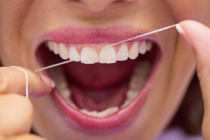 Close-up of female patient flossing her teeth in dental clinic